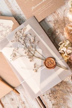 the wedding card is decorated with dried flowers and waxed seal on top of it