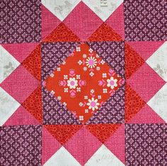 a red and white quilt with pink flowers on the center is featured in this close up photo