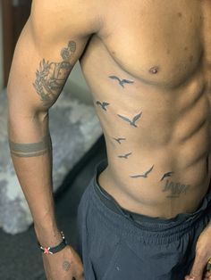 a shirtless man with birds on his chest and arm, looking at the camera