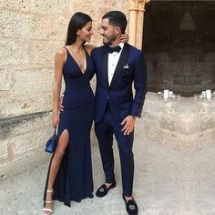 a man in a tuxedo standing next to a woman wearing a blue dress