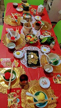 a red table topped with plates and bowls filled with different types of food next to chopsticks