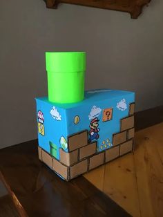 a cardboard box with a green cup on top of it sitting on a wooden table