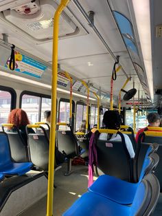 the interior of a public transit bus with blue seats and yellow poles on both sides