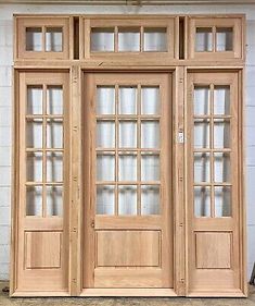 two wooden doors sitting next to each other in front of a white brick wall with windows