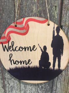 a wooden sign that says welcome home with a silhouette of a soldier and an american flag