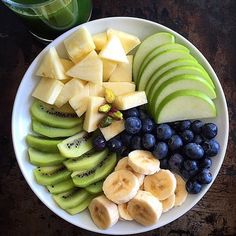 a white plate topped with sliced bananas and blueberries next to a glass of water