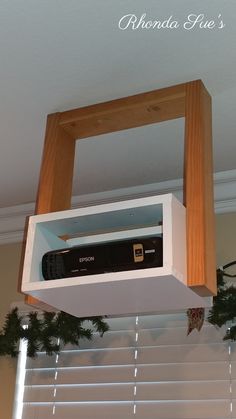 a television sitting on top of a shelf above a window sill with christmas garland hanging from it