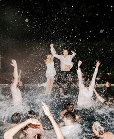 many people are in the water with their hands up