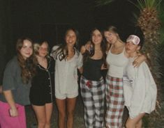 a group of young women standing next to each other in front of a palm tree