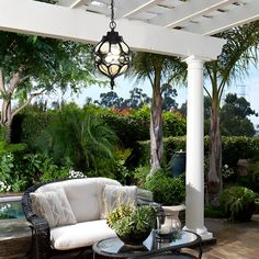 an outdoor living area with wicker furniture and potted plants