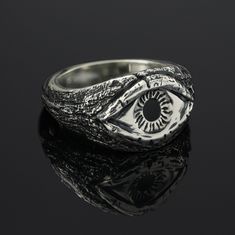 Gaze into the mesmerizing depths of this exquisitely crafted sterling silver ring, featuring the iconic all-seeing eye motif. Meticulously cast from solid .925 sterling silver and enamel, this ring showcases incredible detail and texture, capturing the intensity and mystique of the eye design. The eye is made precisely, drawing the observer into its captivating stare. The surrounding textures and patterns evoke a sense of antiquity, adding to the ring's allure and symbolism. This all-seeing eye Sterling Silver Enamel Ring With Polished Finish, Polished Sterling Silver Enamel Ring In White Gold, Sterling Silver White Gold Enamel Ring With Polished Finish, Polished White Gold Enamel Ring In Sterling Silver, White Gold Enamel Ring With Polished Sterling Silver, Formal Silver Enamel Ring In Sterling Silver, Fine Jewelry Silver Enamel Ring Hallmarked, Silver Hallmarked Enamel Ring, Silver Enamel Ring Hallmarked Fine Jewelry