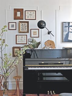 a living room with a black piano and pictures on the wall