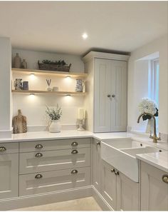 a kitchen with white cabinets and counter tops in front of a window filled with flowers