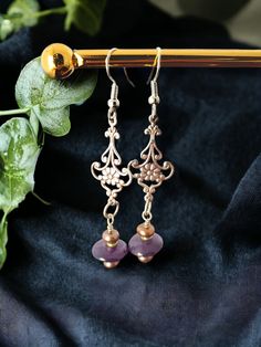 Amethyst and Freshwater Pearl Earrings, a perfect blend of natural beauty and artisanal craftsmanship. These exquisite earrings are thoughtfully designed for those who seek a touch of sophistication and comfort in their everyday adornment. FEATURES: Enchanting Amethyst: Each earring is crowned with a captivating amethyst stone, known for its deep violet hues and associated with qualities of peace, courage, and stability. The amethysts are carefully selected for their vibrant color. Luminous Fres Vintage Earrings With Natural Stones For Gift, Vintage Natural Stone Earrings For Gift, Handmade Amethyst Purple Earrings, Handmade Amethyst Drop Earrings, Artisan Purple Earrings With Ear Wire, Adjustable Purple Earrings With Natural Stones, Purple Dangle Brass Earrings, Purple Artisan Earrings With Ear Wire, Handmade Lavender Crystal Drop Earrings