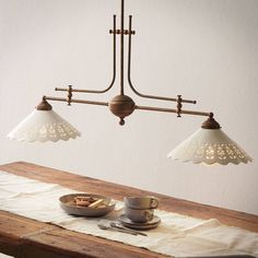 a wooden table topped with two lights and plates of food on top of the table