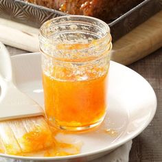 a glass jar filled with liquid sitting on top of a white plate next to a loaf of bread