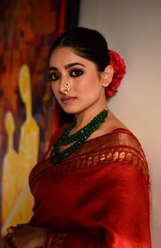 a woman wearing a red sari and gold nose ring