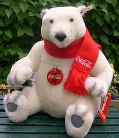 a large white teddy bear sitting on top of a green bench