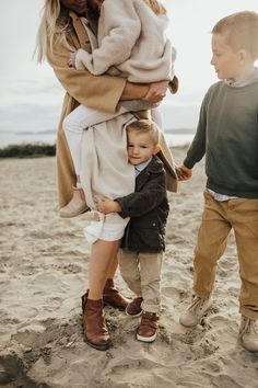 a woman and two children standing on the beach with their arms around each other's shoulders