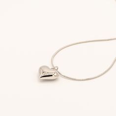 A timeless piece featuring a polished heart pendant on a delicate snake chain. The smooth, dimensional heart catches light from every angle for a simple yet striking effect. Specifications: Finish: White gold platedCore: Titanium steelSize: 41 cm chain + 5 cm extenderClosure: Lobster clasp Silver Double Heart Necklace Tarnish Resistant, Rose Gold Heart Charm Necklace In Stainless Steel, Tarnish Resistant Heart Shaped Sterling Silver Necklace, Elegant Silver Heart Necklace In Stainless Steel, Elegant Silver Stainless Steel Heart Necklace, Minimalist Metal Heart Necklace For Everyday, Heart Pendant Stainless Steel Chain Necklace With Adjustable Chain, Stainless Steel Heart Pendant Chain Necklace With Adjustable Chain, Silver Heart Necklace Tarnish Resistant