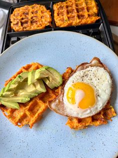 a waffle with an egg and avocado is on a plate next to other waffles