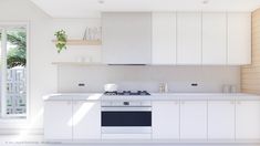 a white kitchen with an oven, dishwasher and window in the back ground