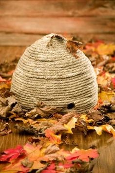 a wooden table topped with lots of leaves and a knitted ball on top of it