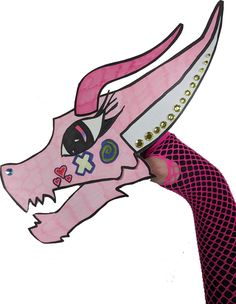 a person holding a paper cut out of a pink dragon with spikes on it's head