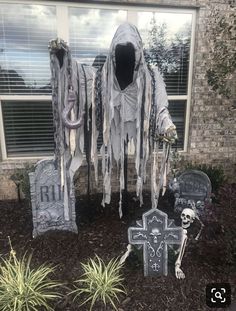 halloween decorations in front of a house with two tombstones and a skeleton on the ground