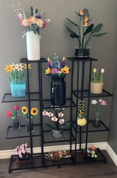 a black shelf filled with vases and flowers