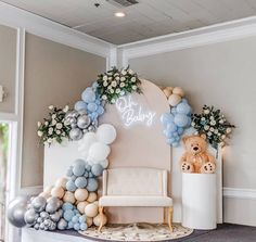 a baby's room decorated with balloons, flowers and a teddy bear sitting on a chair