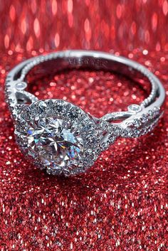 an oval shaped diamond ring on a red glitter background