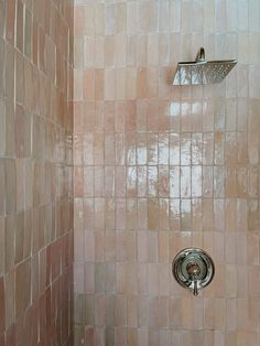 the shower head is mounted to the wall in the bathroom with pink tiles on it