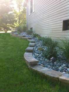 a garden with rocks and grass next to a house