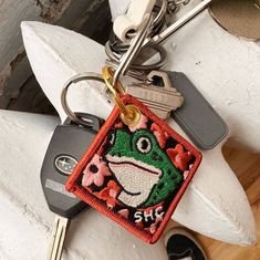 a keychain with a frog on it and some keys hanging from it's sides