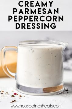 a glass mug filled with creamy parmesan peppercorn dressing on top of a white counter