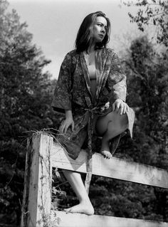 a woman sitting on top of a wooden fence