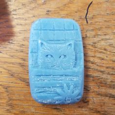 a close up of a blue plastic object on a wooden table with a cat face