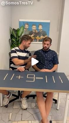 two men sitting at a table in front of a sign that says,'i love you