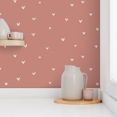 a pink wall with white hearts on it and a wooden shelf in front of the wall