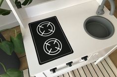 a white stove top oven sitting on top of a wooden floor next to a potted plant