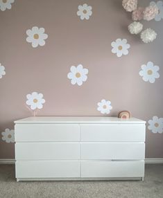 a baby's room with flowers painted on the wall and dresser in front of it