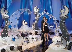 two people standing next to each other in front of an elaborate display with stars and moon decorations