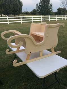 a wooden toy horse drawn sleigh sitting on top of a white table in the grass