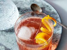 a close up of a drink in a glass with ice and lemon wedges on the rim