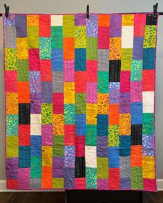 a multicolored quilt hanging on a wall