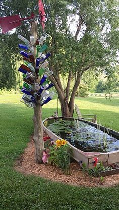 a tree that is next to a pond with bottles on it and flowers in the water