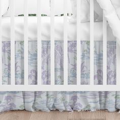 a white crib with purple and green floral bedding