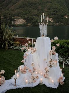 a wedding cake with candles and flowers on the grass