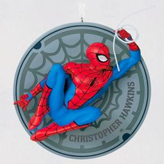 a spider - man ornament hanging from the side of a circular sign that reads,